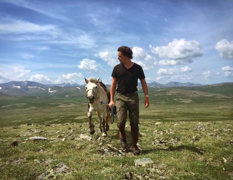 Erik Cooper leading horse Mongolia